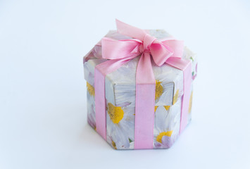 Pink gift box with flowers on it and a pink gift bow. Isolated on white background. Close up