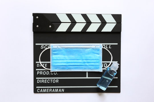 Amedical Face Mask And Hand Sanitizer On Clapperboard Or Film Slate On White Background