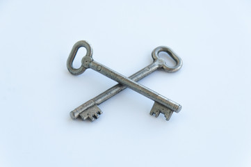 Two crossed retro keys isolated on white background. Metal, silver coloured, rusty door keys crossed