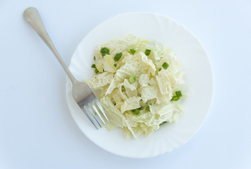 Fresh vegeterian salad on a white plate with a fork. Top view. Mixed salad