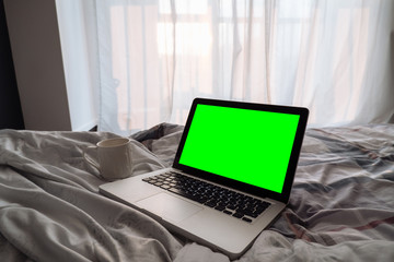one green screen laptop computer on bed.