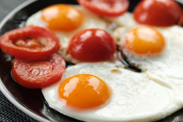 Fried eggs  with tomatoes  for breakfast on a black background.