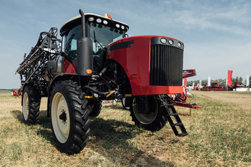 Obraz premium red tractor sprayer in a field at an agricultural exhibition in summer