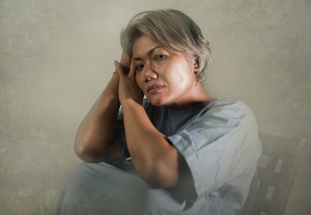 dramatic portrait of attractive sad and depressed mature woman with grey hair in pain suffering...