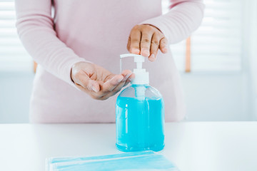 Woman using a hand sanitizer alcohol gel to wash hands to prevent viruses and diseases at home