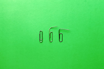 The concept of loneliness. The psychology of relationships. Paper clips on a green background. Flat lay