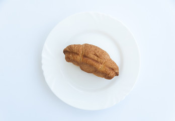 Croissant on white plate. Sweat baked dessert in a dish. Top view