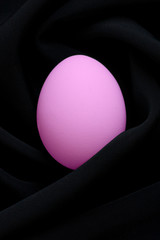 Purple easter egg on black silk fabric