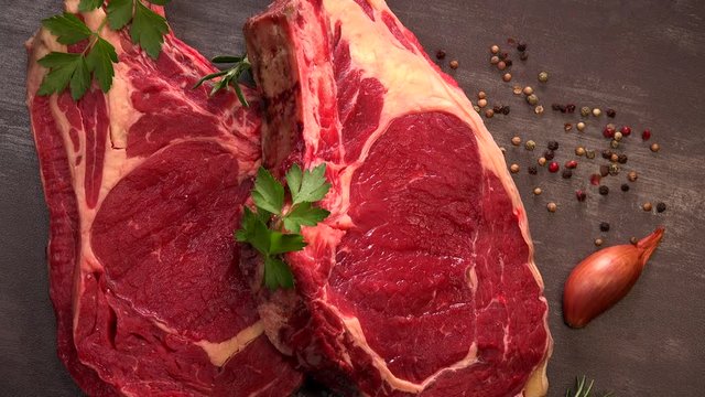 Raw T Bone steak on wooden board prepared to Grill on turntable