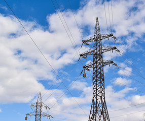 Metal support for high voltage power lines against a blue sky. Electrical cables are attached to...