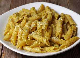 Penne rigate condite con pesto di basilico tipico della cucina tradizionale ligure. Pasta italiana.