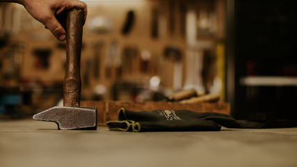 Les mains d'un artisan et son marteau dans son atelier