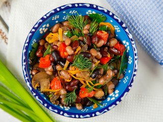 Vegetarian food, protein food, salad of three types of beans with fried mushrooms, carrots and bell pepper with herbs. Top view.