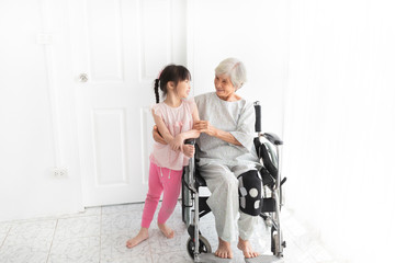 Fototapeta na wymiar old asian female hug asian children, they feeling happy and smile, old asian people sitting on wheelchair, elderly healthcare promotion, happiness family activity