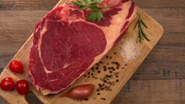 Raw T Bone steak on wooden board prepared to Grill on turntable