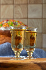 Two servings of strong alcohol on the background of a festive cake decorated with colored candied fruits. Concept: friendly gatherings. Vertical.