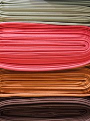 Bright yellow and blue fabric laid in layers, close-up. Background with a bright and expressive fabric texture. Assortment of multi-colored fabrics in the store