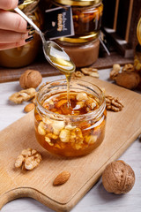 Obraz na płótnie Canvas Jar of honey on a wooden board. Honey with nuts.