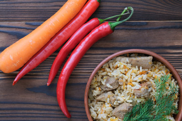 Pilaf with meat in a clay plate with herbs