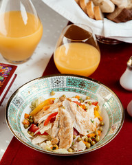 chicken salad with peppers peas and a glass of orange juice