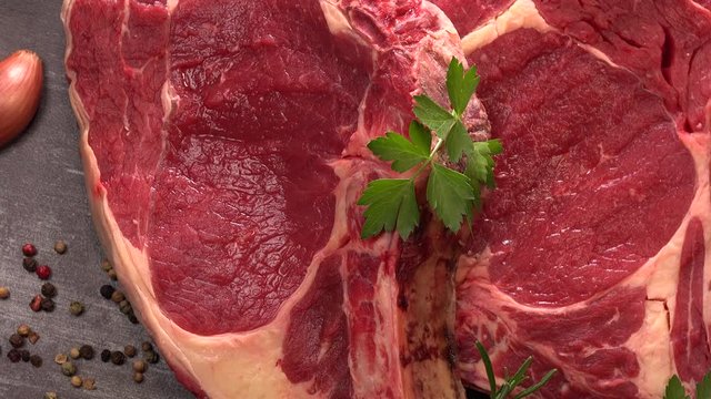 Raw T Bone steak on wooden board prepared to Grill on turntable
