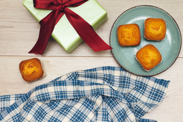 homemade madeleine sponge cake and gif box on wood table, holiday celebration