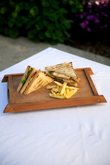 club sandwich and french fries on a wooden tray