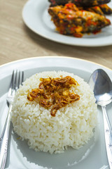 Nasi putih or white rice in white plate with fried shallot on the top.