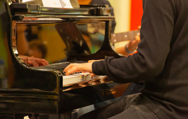 A close up of a hand that is playing a black electric piano in a musical performance for education