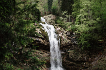 Fototapeta na wymiar Wasserfall in einem Wald mit einer Brücke