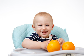 Cheerful little boy is eating oranges on a white background