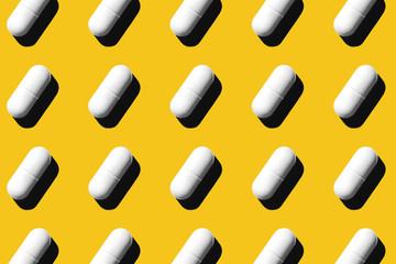 Trendy pattern made with Pharmaceutical medicine white pills on yellow background. Medicine creative concepts. Minimal style with colorful paper backdrop. Trendy color of the year 2020.