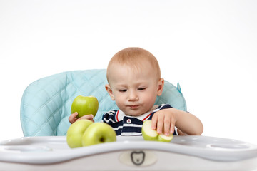 Cheerful little boy is eating green apples on a white background