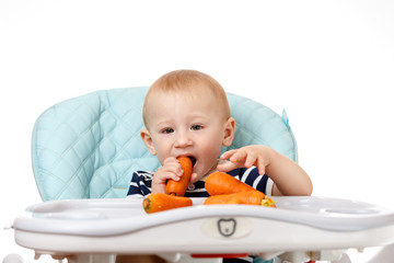 Cheerful little boy is eating carrot on a white background