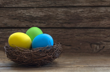 Easter decoration with colorful eggs in nest and rustic background. Easter eggs in a nest