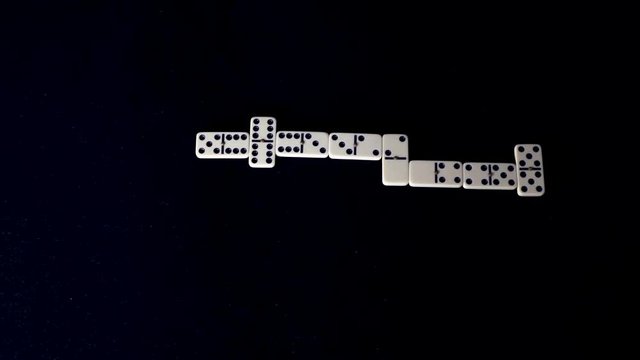 Domino game with all pieces placed one by one on black table, timelapse board game concept