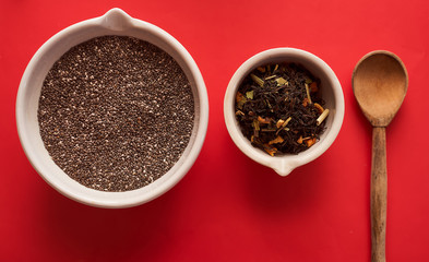 chia seeds and fruit tea in white bowls and a wooden spoon on a red background top view
