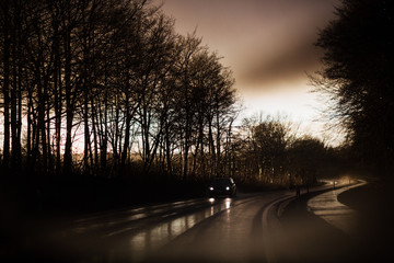 Unwirkliches Licht bei einem Unwetter über einer nassen Strasse mit einem Auto