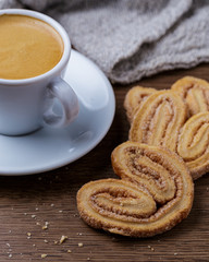 Xícara de café com biscoitos espalhado sobre mesa de madeira