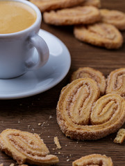 Xícara de café com biscoitos espalhado sobre mesa de madeira