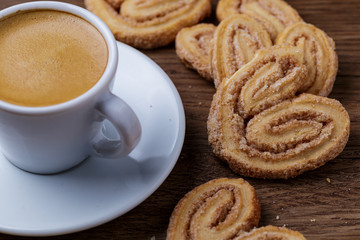 Xícara de café com biscoitos espalhado sobre mesa de madeira