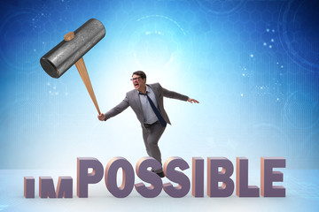 Businessman hitting the word impossible with hammer