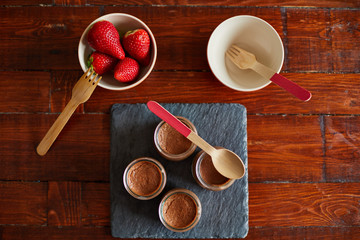 Dessert: strawberries and chocolate yogurt in a bowl on wooden table.