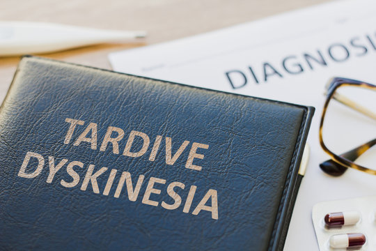 Diagnosis and Book about Tardive Dyskinesia and medication, thermometer and pills. Medic concept