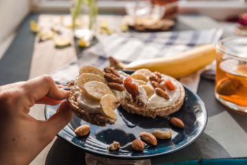 eating a toast on a blue plate. hand holding toast. breakfast at home. cup of tea with lemon and banana and almond toast. breakfast at home. breakfast idea. simple breakfast decoration