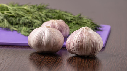 Garlic and dill are on the cutting Board.