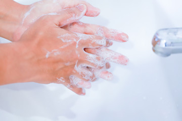 young women washing hands with soap rubbing fingers and skin on white basin