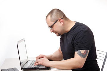 A man sits at a table with glasses and works on a laptop. On a white background.