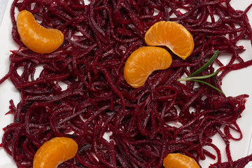 Two slices of tangerine on sliced fermented beets