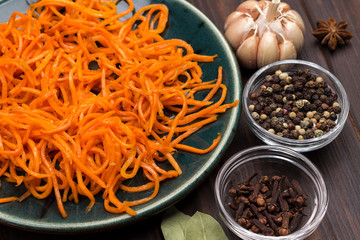 Fermented carrots in plate. Spices, garlic and parsley on table.